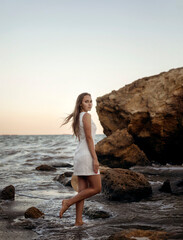 A person standing in front of a rock next to a body of water