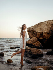 A person standing in front of a rock next to a body of water