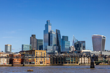 London skyline with modern skyscrapers, River Thames, and Millennium Bridge on a clear day.