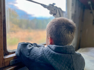 Child gazing out train window on journey