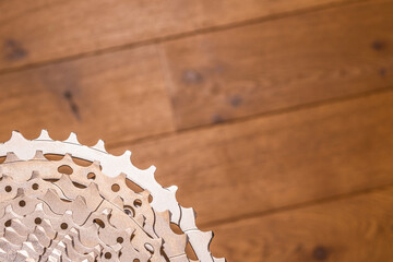 Close-up of a multi-sprocket bicycle cassette resting on wood flooring, showing gear progression and hub interface