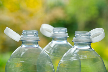 Plastic bottles with so-called tethered caps against a green blurry background. The caps are attached to the drink bottle to prevent it from ending up in nature. The EU bans loose closures and caps.	