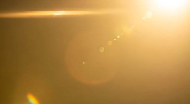 Bright golden sun flare with lens effects in warm sky