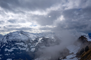 Winter veil drapes snowed Swiss Alps as clouds drift over Hoch-Ybrig peaks.