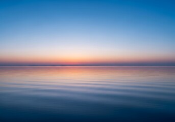 Fototapeta premium Serene expanse of water meets the horizon beneath a gradient sky