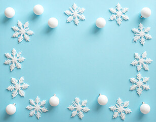 Serene Winter Flat Lay Border of Glittering Snowflakes and White Baubles on Pastel Blue.