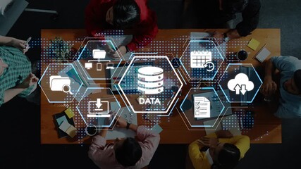 A diverse group of professionals engages in a strategic meeting focused on data management, featuring digital graphics that symbolize technology and collaboration. Raster - Powered by Adobe