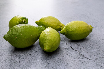 Fresh green limes scattered on a gray stone surface