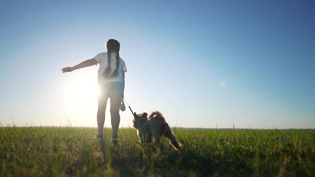 Girl child running with a dog in a park in nature. Family park happy concept. Daughter runs with a dog in nature. A girl and her dog are park running in the nature.