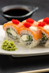 Salmon sushi rolls with cream cheese, red roe, soy sauce, wasabi and ginger, top view