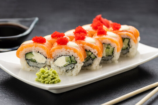 Salmon sushi rolls with cream cheese, red roe, soy sauce, wasabi and ginger, top view