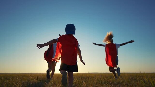 A group of kids are running around with superheroes. Hero super child concept. Group of children running together, silhouette lifestyle of. superheroes. A group of kids run together like superheroes.