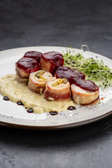 Chicken bacon roulade with berry sauce and creamy puree, plated with microgreens