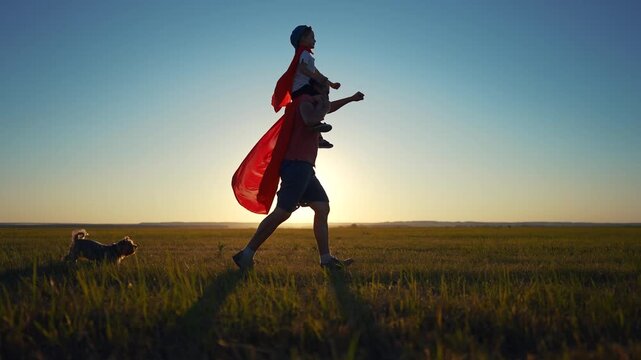 Father and son running superhero silhouette. Child family super concept. Silhouette of a superhero with his daddy and baby. Silhouette of superhero with father and son grass running on.