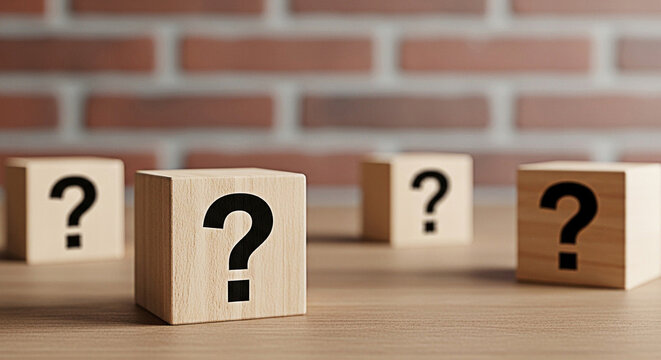 Wooden blocks displaying question marks on a wooden surface against a brick wall background create a sense of mystery and uncertainty
