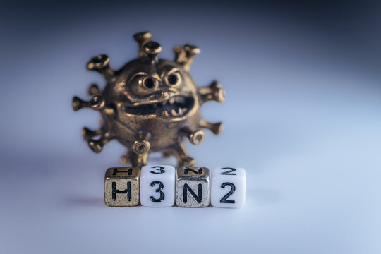 3D illustration of a virus model with a menacing expression, accompanied by lettered dice spelling H3N2, representing infectious disease and health awareness concepts