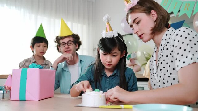 Caucasian mother cutting cake while family congratulate in girl's birthday. Diverse family celebrate daughter important day while waiting for eating dessert and food while smiling together. Pedagogy.