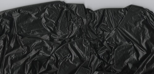 Crumpled black plastic texture with intricate folds and wrinkles creating an abstract, grunge background. Ideal for environmental, industrial, or design projects.