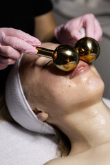Fototapeta premium Face massage with a heavy golden equipment of different temperature