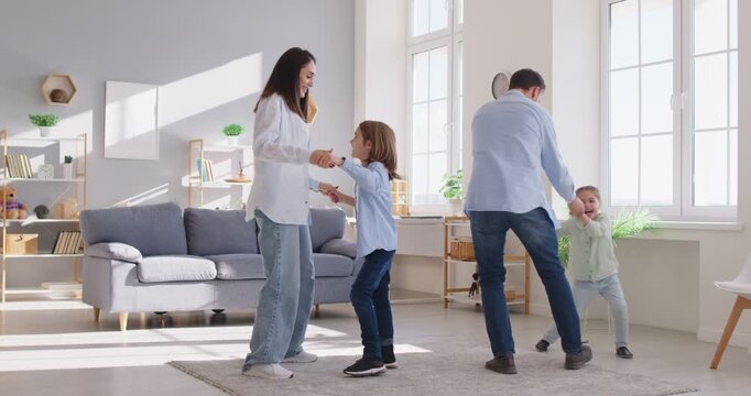 Positive family with a son and daughter enjoying leisure time at home, dancing and playing together. The fun and affectionate atmosphere showcases love, togetherness, and joyful bonding.