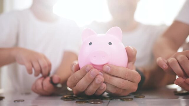 Family with children in their hands is holding a piggy bank. coin finance money concept. a family of children saving coins. a family of children lifestyle is holding coins in a piggy bank.