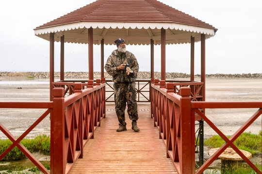 Senior man bird watching and photographing in wetland