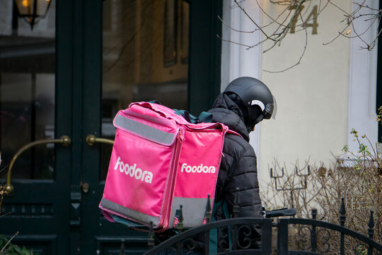 OSLO, NORWAY - NOVEMBER 21, 2025: Foodora Delivery Person with Pink Thermal Backpack on City Street