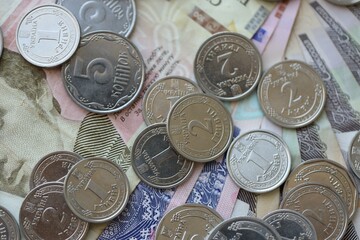Ukraine money coins lying on mixed hryvnia banknotes. Finance background concept.