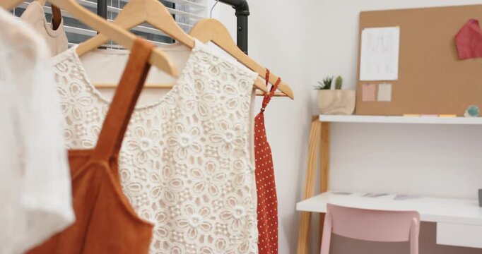 Starting with focus on wooden clothing rack, camera panning to reveal design workspace, copy space