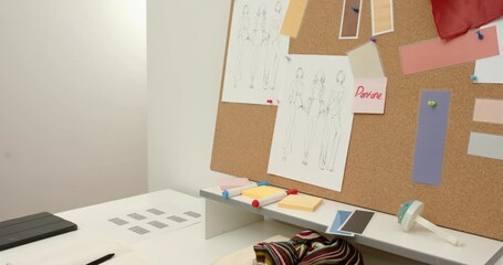 Camera starting slow pan across design desk and corkboard, revealing pinned sketches and swatches - Powered by Adobe