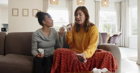 Diverse female friends sitting at home using tissues while comforting after reading phone message