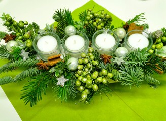 Advent wreath or tabletop arrangement with four white candles and green branches