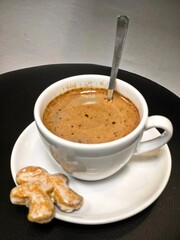 Hot chocolate or coffee or cocoa in a white cup with gingerbread on a black background