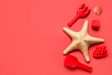 Composition with beach sand molds, starfish, toy rake and shovel on red background