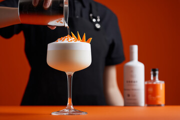 Craft cocktail creation with vibrant orange garnish being expertly poured, promising a refreshing and sophisticated beverage experience for discerning palates
