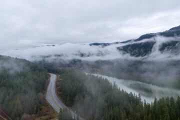 Mist Shrouded Highway Winding Through Forested Mountains Beside a Quiet BC River Valley Landscape