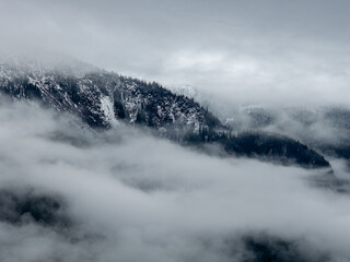 Snowy Mountain Ridge Shrouded in Fog Over Cloudy BC Landscape in Canada
