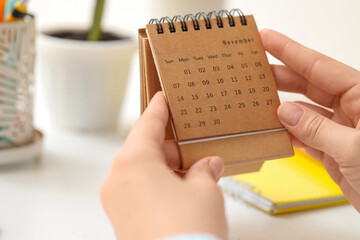 Female hands with flip calendar at table, closeup