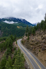 Winding Mountain Road Through Conifer Forest in British Columbia, Canada Under Cloudy Sky