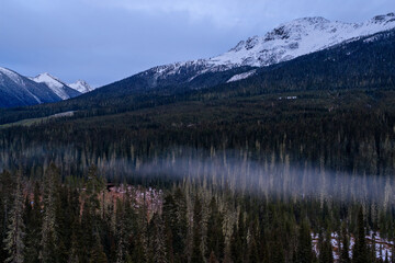 Snowy Mountain Range Over Dense Forest in BC, Canada With Misty Morning Valley
