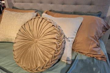 Close Up Of A Bed With Multiple Cushions And Pillows In Various Textures And Colors.