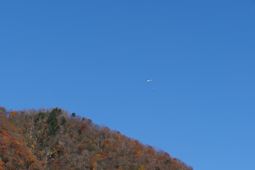 紅葉の山と物資を運ぶヘリコプター