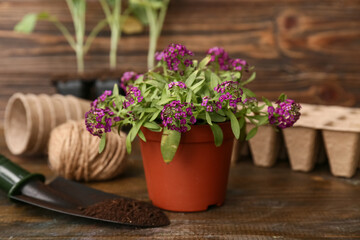 Pot with flowers and gardening shovel on wooden background