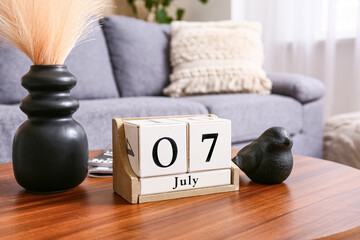 Cube calendar with date 7 JULY and decor on table in living room, closeup