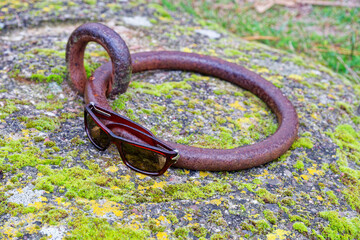 Metal mooring ring in stone beside sunglasses on ground