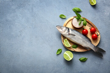 Wooden plate with fresh raw seabass fish and different ingredients on blue background