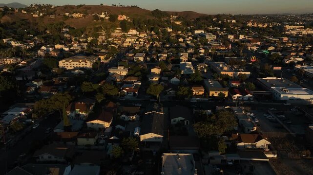 The sun sets on homes and a church in the historic Lincoln Heights neighborhood of Los Angeles, California, USA.