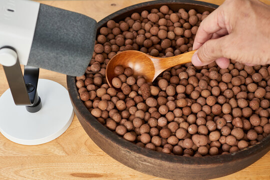 Scooping clay pebbles with wooden spoon for relaxation ASMR audio recording.