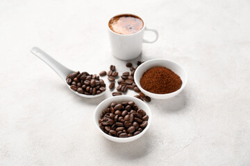 Cup of coffee with beans and powder on light background