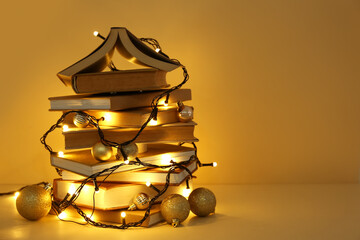 Fototapeta premium Christmas tree made of different books and garland on yellow background